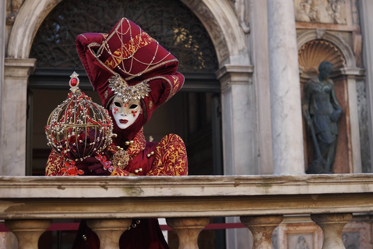 Person in elaborate Venice Carnival costume and traditional Venetian mask posing in a piazza